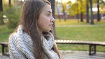 Close-up of the face of woman who drinks hot tea or coffee in autumn park, she wears knitted scarf. girl drinks coffee for good mood from mug video