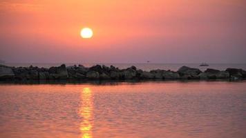 4k escénico amanecer rojo sol de fondo. video de cerca del sol naciente detrás del mar