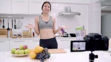 Blogger sporty Asian woman using camera recording how to make apple juice video for her subscriber.