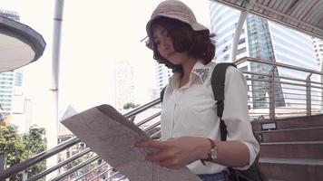 donna asiatica backpacker direzione e guardando sulla mappa della posizione durante il viaggio a bangkok, thailandia. video