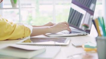 Beautiful young smiling asian woman working laptop on desk in living room at home. video