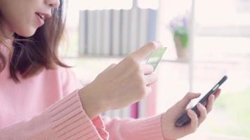 vacker asiatisk kvinna som använder smartphonen som köper online-shopping med kreditkort. video