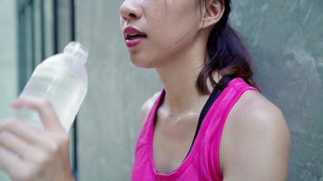 Slow motion - Healthy beautiful young Asian runner woman drinking water. video