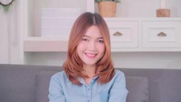 adolescent femme asiatique se sentir heureux souriant et regardant la caméra tout en se détendant dans son salon à la maison video
