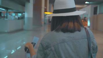 slow motion - gelukkig Aziatische vrouw met trolley of kar met veel bagage wandelen in terminal hal. video