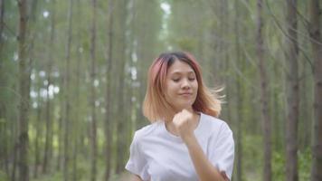 mujer joven hermosa sana atlética deportiva asiática corredor en ropa deportiva corriendo y trotando en la pista forestal. video