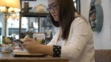 kvinna som använder smart telefon och skriver anteckningar i restaurangen. video