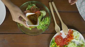 bovenaanzicht van gezondheidsbewuste jonge chef-vrouw gooien een smakelijke biologische groene salade.