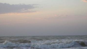 Waves crashing on the shore at sunset.