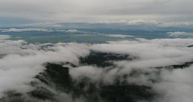 Aerial view wide shot point of view mountain with lush trees and foggy clouds