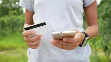 kvinnans händer som håller ett kreditkort och använder smart telefon för online-shopping
