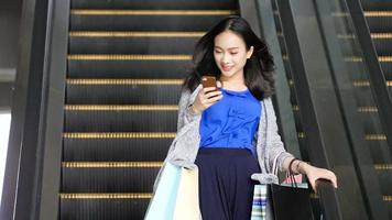 Asian girl finishes shopping and comes down the escalator video