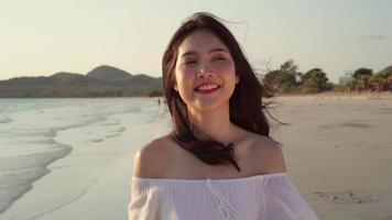 hermosa mujer feliz relajarse caminando en la playa cerca del mar al atardecer en la noche. video