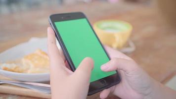 joven asiática con dispositivo de teléfono móvil negro con pantalla verde. video