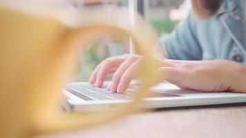 mujer asiática independiente de negocios trabajando, haciendo proyectos en la computadora portátil en la cafetería. video