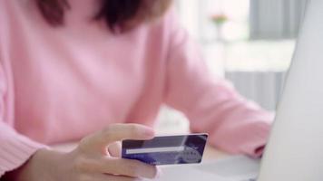 belle femme asiatique utilisant un ordinateur ou un ordinateur portable, acheter des achats en ligne par carte de crédit. video