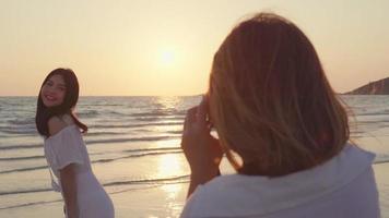 junge asiatische Freunde, die eine Kamera benutzen, die Fotos voneinander am Strand macht video