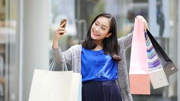 menina asiática tira selfie na frente da loja.
