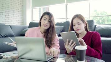 donne asiatiche che utilizzano un laptop per lavorare sul loro budget nel soggiorno di casa