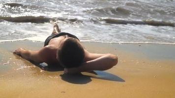 joven yace en la arena junto al mar