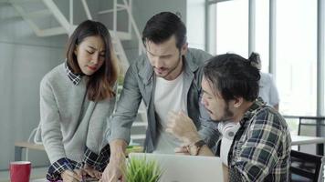 Group of casually dressed business people discussing ideas in smart casual wear working on laptop. video