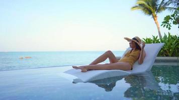 Woman sitting at lounge chair in swimming pool video