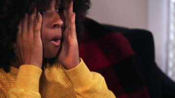Excited young black woman watching tv video