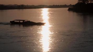 silhouet van een houten boot die vaart tijdens een prachtige zonsondergang video