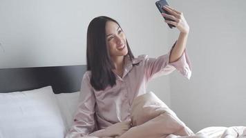 Joven mujer asiática tomando selfies en la cama video