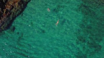 Vista superior de una niña nadando en el mar en 4k video
