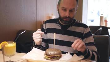 un homme barbu mangeant un hamburger video