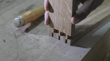 a joiner in an apron cuts a dovetail joint video