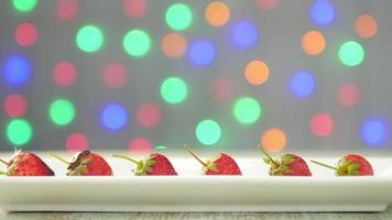 Liquid chocolate poring to strawberry over colorful light bokeh background