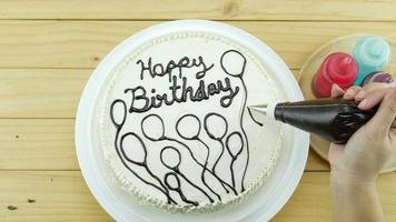 Woman is drawing chocolate on top of birthday butter cake decoration video