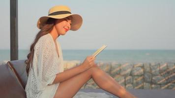 jeune femme asiatique lisant un livre au bord de la mer