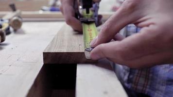 close-up handen die de lengte van het bord meten met een metalen meetlint. werknemer maakt metingen op een houten bord met een meetlint. 4k. 4k-video. slow motion. 24 fps video