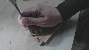 close-up, timmerman een zwaluwstaart maken op een houten onderdeel met een beitel en een hamer video