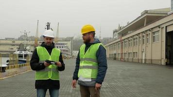 twee werkende mannen bespreken een project terwijl ze op een haven staan video