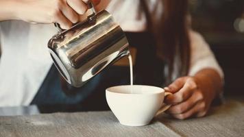 Primer plano de una mujer barista profesional vertiendo leche en café con leche video