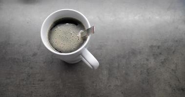 Tasse Kaffee mit weißem Schaum und mit einem Löffel auf einem Tisch video