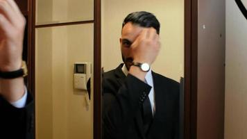 Man fixing his hair and suit in front of a mirror video