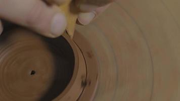 Craftsman removes excess clay from the lid for a teapot video
