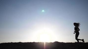 Silhouette of a woman running across video