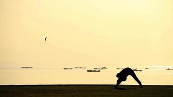 El hombre entrenamiento deportivo de sombra en la playa al amanecer.