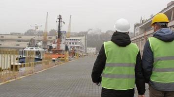 Port workers in helmets go to the port and talk video