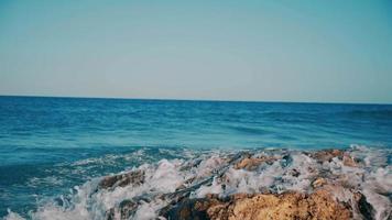 Olas del mar azul rompiendo sobre una roca video