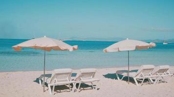 cadeiras de praia em uma praia limpa com vista para um mar azul transparente