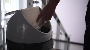 Hand throwing the bottle into the bin. video