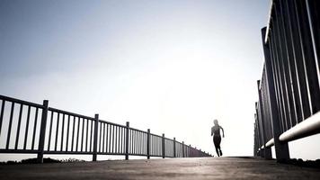 silueta de mujer corriendo en el puente al amanecer video