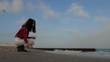A girl throws pebbles at the sea